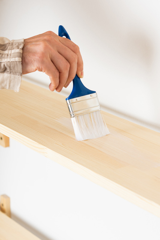 Painter varnishes the bookshelf